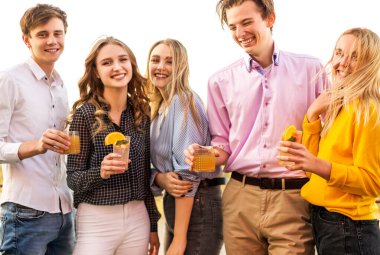 Mutlu erkekler ve kadınlar, kokteyl bardaklarını tokuşturuyor ve parti boyunca kadeh kaldırmayı teklif ediyorlar.