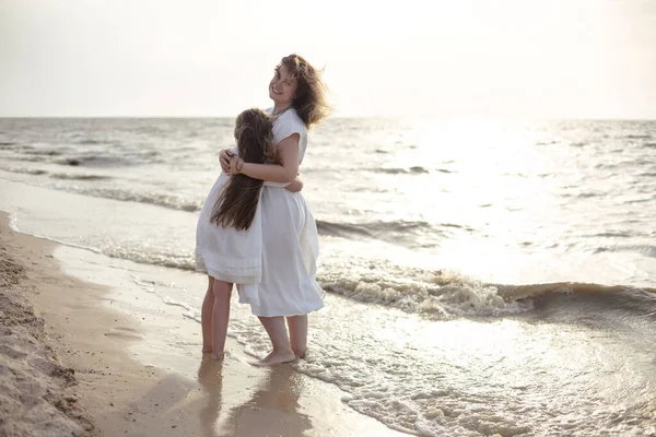 フルボディ陽気女性で白いドレスを身に着けています女の子を受け入れながらビーチに立って近くに手を振っ海で朝 — ストック写真