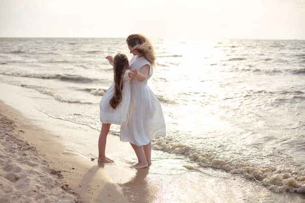 フルボディ陽気女性で白いドレスを身に着けています女の子を受け入れながらビーチに立って近くに手を振っ海で朝 — ストック写真