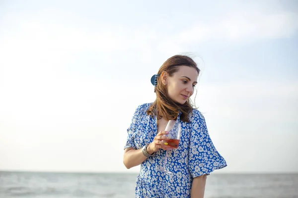 海の近くの砂浜でワインを楽しみながら笑顔と離れて見て夏服の大人の女性 — ストック写真