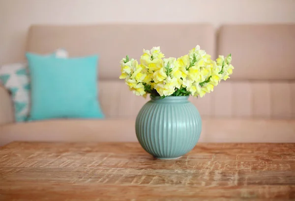 ミニマリストモダンなスタイルのインテリアと空のアパート 背景にソファと居心地の良いリビングルームで青い花瓶に黄色の花の花束と木製コーヒーテーブル 選択的フォーカス — ストック写真