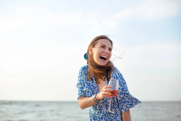 海の近くの砂浜でワインを楽しみながら笑顔と離れて見て夏の衣装で幸せな大人の女性 — ストック写真