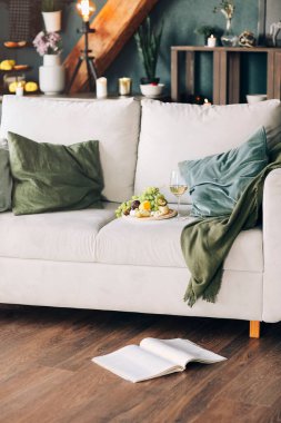 Evde şık bir odada yastıkların yanına konmuş taze meyve ve bir bardak şarap tabağı.