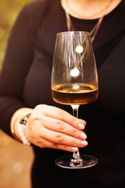 Siyah elbiseli tanınmayan bir kadın güneşli bir yaz gününde beyaz şarabın tadını çıkarıyor.