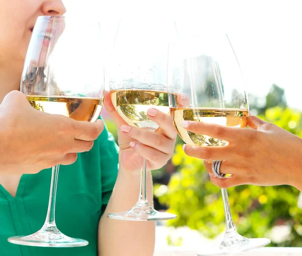 Group of anonymous people clinking wineglasses and proposing toast during party outdoors