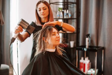 Kuaförde kuaförlük yapan mutlu bir kadın. Yetenekli kadın kuaför esmer bayan müşteriyle kuaförde ne yapacağına karar veriyor. İki güzel bayan yeni saç stilini tartışıyor. Profesyonel kuaför ve stilist çalışma konsepti