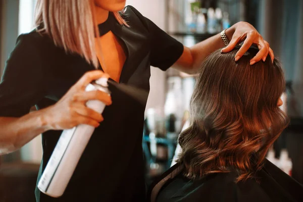 美容院的美发过程 女性理发师用喷雾固定客户女性头发的剪下来的照片 并在为客户做卷发时进行护理治疗 美容美发服务 — 图库照片