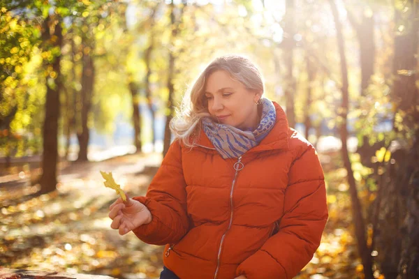 在秋日的阳光明媚的周末 身穿外套 面带微笑 用干叶遮住眼睛的快乐女性 — 图库照片