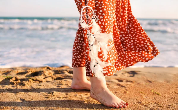 砂浜の海辺を裸足で歩く女性の写真を切り取り 夢のキャッチャーを押さえつけ 夏の天気を楽しむロングドレスの女性と 休暇中の新鮮な塩辛い海の風 — ストック写真