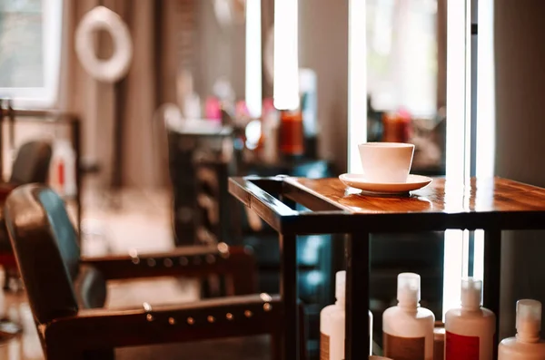 美容室のインテリア 誰もいない美容室の顧客のための木製テーブルと椅子のコーヒーカップ 背景のぼやけた鏡 空の美容室の職場 — ストック写真