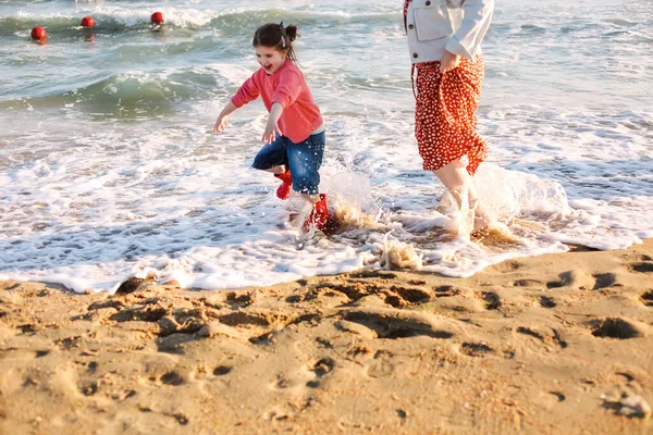 笑顔の娘と一緒に夏の海辺で一緒に過ごす時間を楽しんで 日当たりの良いビーチで彼女に向かって実行している若い愛情のある母親 幸せなお母さん抱擁の女の子 — ストック写真