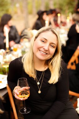 Mutlu bayan konuk gülerek ve kadeh tokuşturarak sonbahar günü şölen sırasında tost teklif ederken.