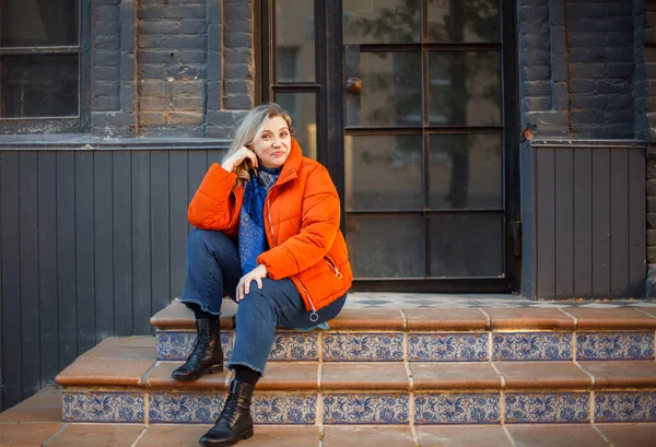 Feliz Sonriente Mujer Mediana Edad Chaqueta Naranja Sentada Escaleras Hormigón —  Fotos de Stock