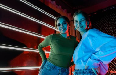 En iyi iki mutlu bayan arkadaşın selfie portresi, şık giyinmiş doğal makyajlı genç kızlar birbirlerine omuzlarından sarılıyorlar, disko partisinde eğleniyorlar ve kameraya gülümsüyorlar.