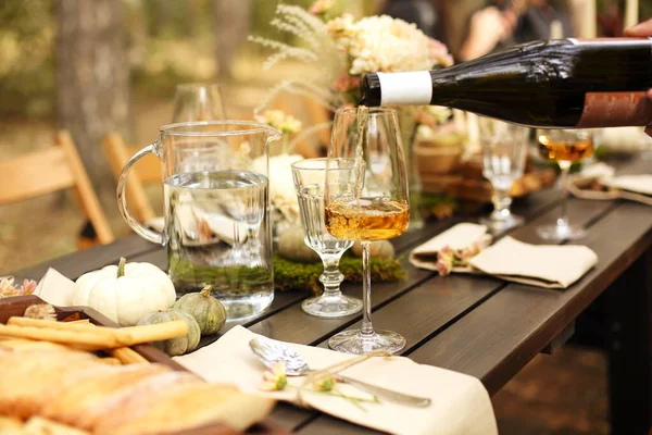 食器の近くに置かれたオレンジワインのグラスと 庭の秋の日に木製のテーブルの上に並べられた果物の中に新鮮な花の花束 季節のパーティーやお祝い — ストック写真