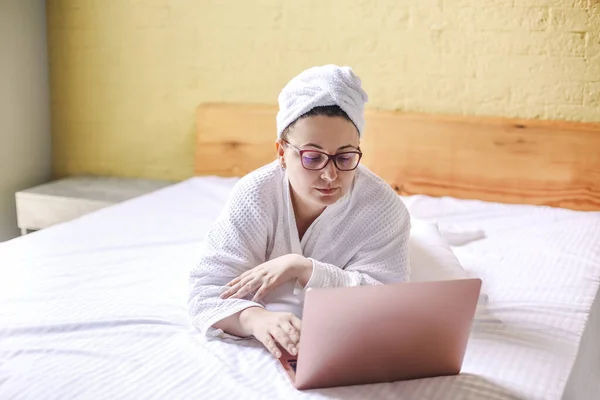 Szczęśliwa Kobieta Okularach Czeka Wideo Połączenie Laptopie Leżącym Łóżku Praca — Zdjęcie stockowe