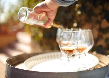 Sonbahar bağında birçok bardak ve bir şişe gül şarabı, degukasyon konsepti. Bardağa şarap dökülüyor.