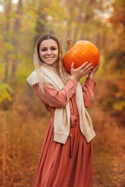 黒いケープの若い女性が不気味なジャック ランタンを持っており 秋の森の中でハロウィーンの日に離れて見て — ストック写真