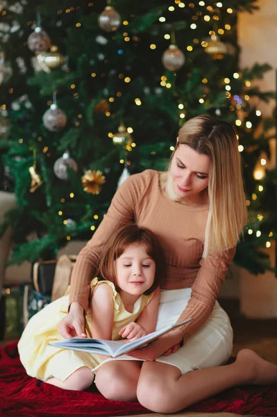 在寒冬的圣诞假期 快乐的奶奶和小女儿一起坐在沙发上看书 一边在家里度过 一边抱着孩子 一边披着毛毯 — 图库照片
