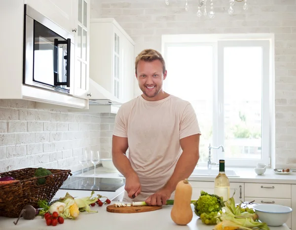 Muž vaří doma a připravuje salát v kuchyni — Stock fotografie