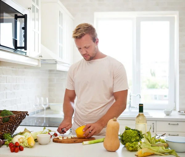 Bonito homem cozinhar em casa preparando salada na cozinha — Fotografia de Stock