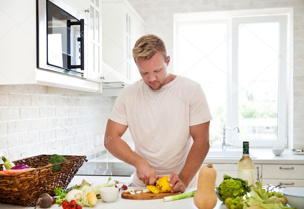 Man cooking at home preparing salad in kitchen