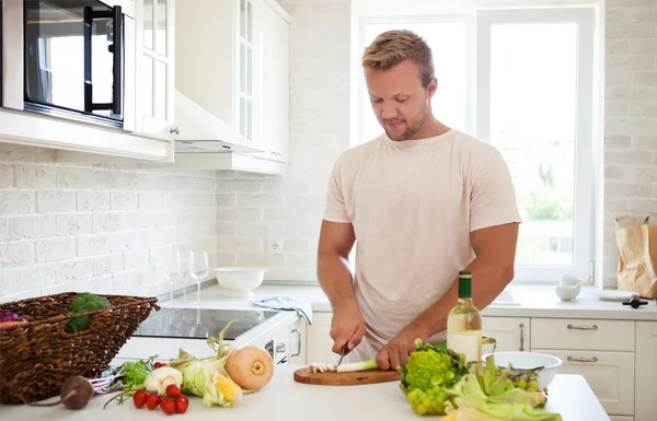 Knappe man koken thuis bereiden salade in de keuken — Stockfoto