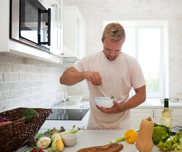 Bell'uomo che cucina a casa preparando l'insalata in cucina — Foto Stock