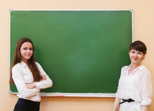 Student girls standing near blackboard — Stock Photo, Image
