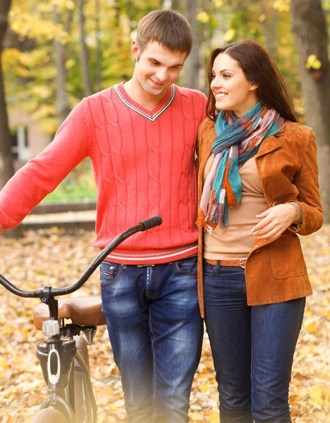 Happy young couple with bicycle in autumn park — Stock Photo, Image