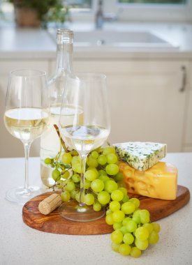 çeşitli türlü peynir, üzüm ve iki bardak beyaz kazanmak