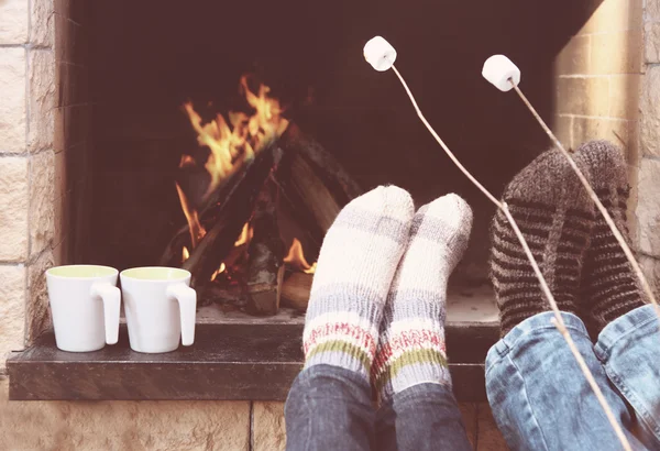 Los pies de la pareja calentándose en una chimenea —  Fotos de Stock