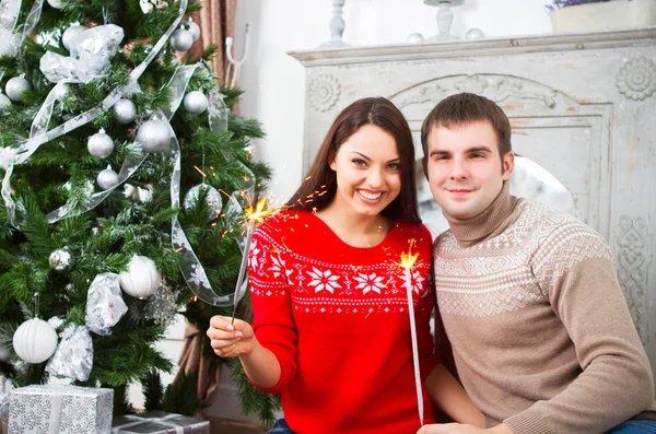 Pareja joven sentada junto al árbol de Navidad — Foto de Stock