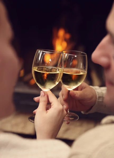 Romantico giovane coppia tostatura bicchieri di vino di fronte al fuoco acceso — Foto Stock