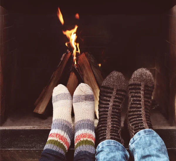 Patas románticas de una pareja en calcetines frente a la chimenea en invierno — Foto de Stock