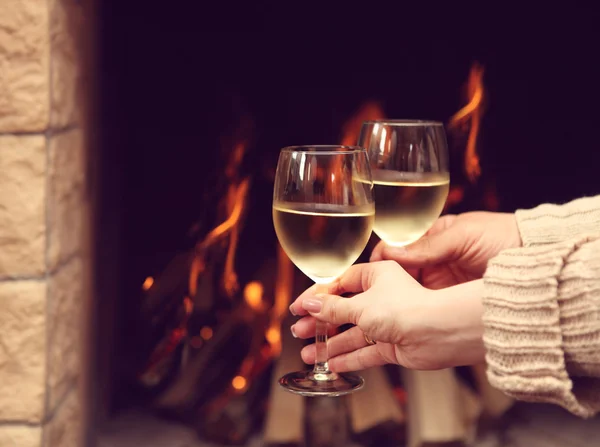 Un par de copas de vino tostadas frente a la chimenea encendida —  Fotos de Stock