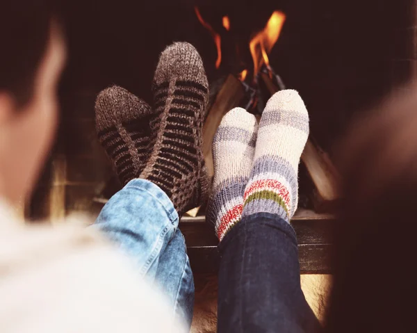 Patas románticas de una pareja en calcetines frente a la chimenea en invierno — Foto de Stock