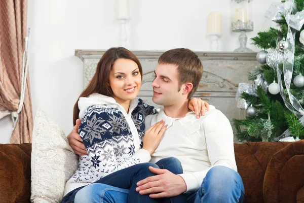 Joven pareja feliz sentada junto al árbol de Navidad — Foto de Stock