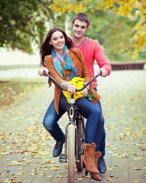 Lyckliga paret med cykel i höst park — Stockfoto