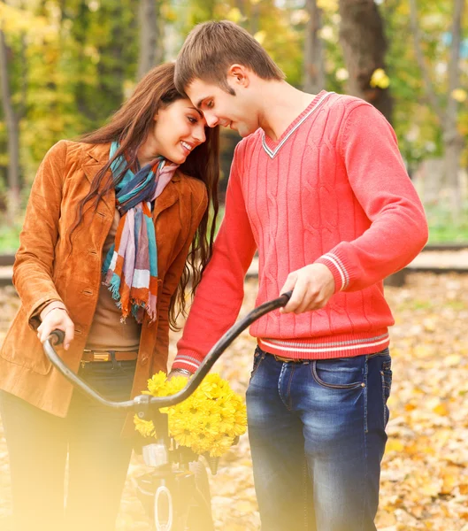 Pareja feliz con bicicleta en el parque de otoño —  Fotos de Stock