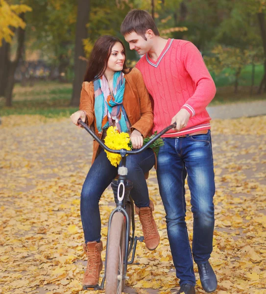 Pareja feliz con bicicleta en el parque de otoño —  Fotos de Stock