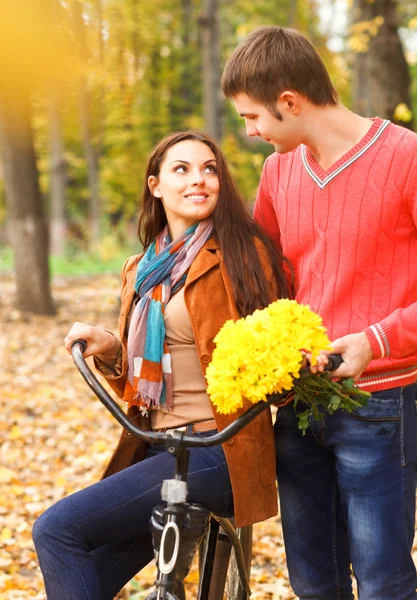 Счастливая пара с велосипедом в осеннем парке — стоковое фото