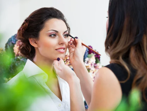 Maquilhadora fazendo maquiagem para a noiva bonita jovem — Fotografia de Stock