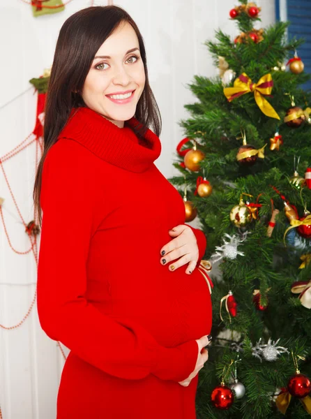 Mujer embarazada feliz sentada cerca del árbol de Navidad — Foto de Stock