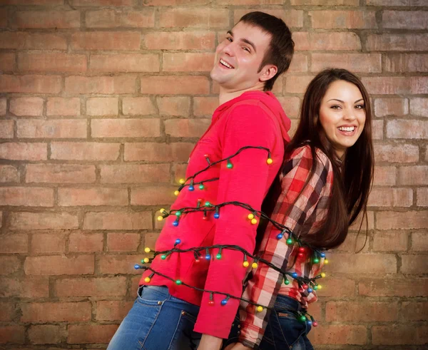 Šťastný mladý pár u cihlové zdi s věnec — Stock fotografie