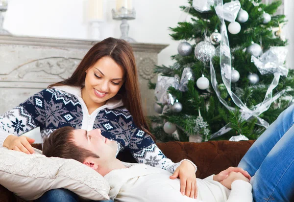 Jovem casal feliz no sofá por árvore Cristmas — Fotografia de Stock