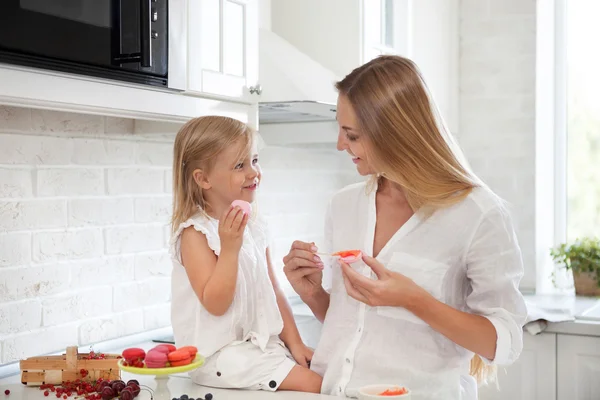 Mujer cocinando macarrones en la cocina con su hijita — Foto de Stock