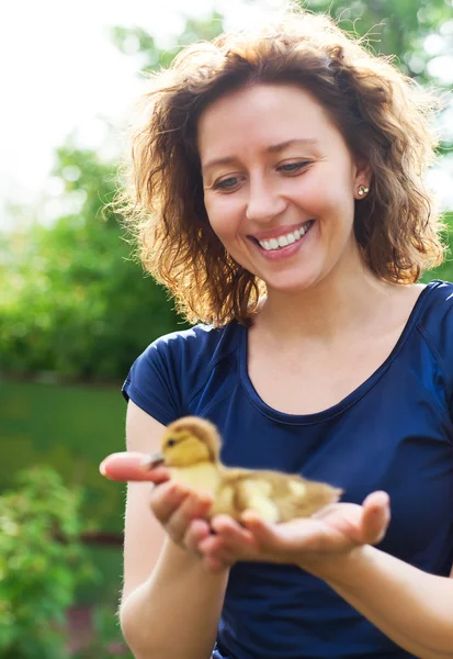 Woman holding little yellow duckling in her hands — Stock Photo, Image