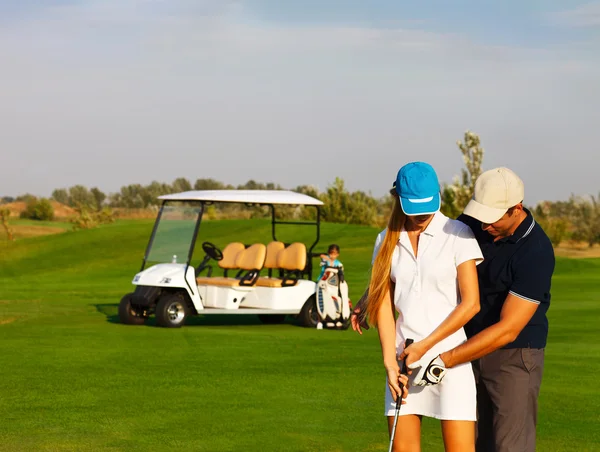 Pareja deportiva jugando al golf en un campo de golf —  Fotos de Stock