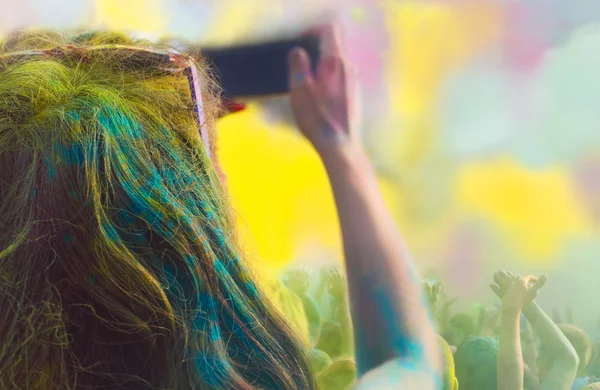 Mujer tomando fotos en el teléfono móvil en el festival de color holi — Foto de Stock